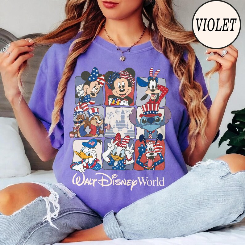 May include: A violet t-shirt featuring a grid of Disney characters in patriotic attire. Mickey and Minnie Mouse, Donald and Daisy Duck, Goofy, Chip and Dale, and Stitch are depicted with red, white, and blue designs. The text "Walt Disney World" is printed at the bottom.