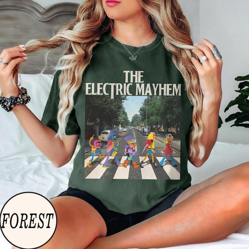 Pode incluir: T-shirt verde escuro com gr&aacute;fico "The Electric Mayhem". O gr&aacute;fico mostra personagens dos Muppets atravessando uma rua. A camiseta tem um corte folgado.