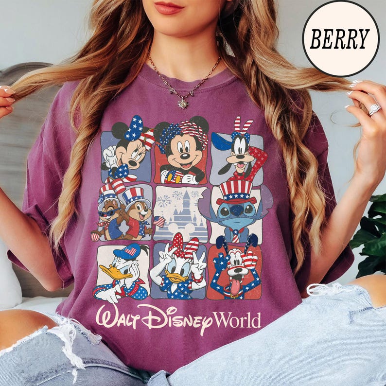 May include: Berry-colored t-shirt featuring a grid of Disney characters in patriotic attire. Mickey Mouse, Minnie Mouse, Donald Duck, and Stitch are among the characters. The words "Walt Disney World" are printed at the bottom.