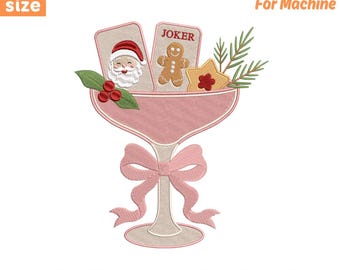 May include: An embroidery design for machine featuring a pink cocktail glass with a bow, containing a Santa Claus card, a gingerbread man labeled JOKER, a star cookie, and pine sprigs. Text includes 5 size 4" 5" 6" 7" 8" and file formats PES DST EXP JEF VP3 HUS XXX.