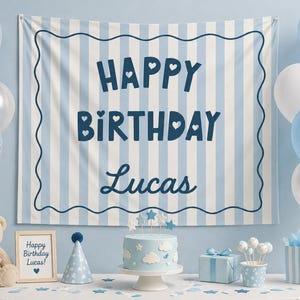 May include: A birthday party scene with a blue and white striped backdrop that reads "Happy Birthday Lucas". Balloons, a cake, gifts, and a teddy bear are also present, creating a festive atmosphere.