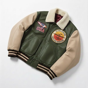 Puede incluir: Chaqueta universitaria verde y beige con cuello crema. Parches en la chaqueta con las palabras "USA" y "Flying Legends American Airborne". Las mangas son beige, y los puños y el dobladillo tienen rayas marrones y crema.