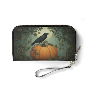 May include: A black zippered wallet featuring a Halloween-themed design. The image depicts a black crow perched on an orange pumpkin, set against a backdrop of a full moon and a forest with vines.