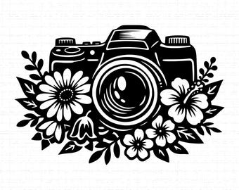 May include: A black and white illustration featuring a camera design encircled by floral elements. The camera, with its lens and body details, is the central focus. Flowers and leaves surround the camera, creating a decorative design for photographers.