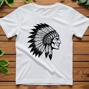 May include: White t-shirt featuring a black and white graphic of a Native American chief in profile, wearing a feathered headdress. The design is centered on the shirt, showcasing the detailed illustration. The shirt is made of a soft material.