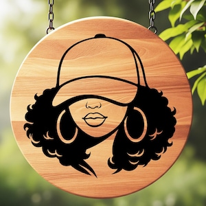 May include: A round wooden sign with a black graphic of a woman wearing a baseball cap and hoop earrings. The sign is hanging from two chains and has a natural wood grain finish.