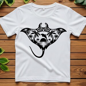 May include: White t-shirt featuring a black graphic of a manta ray with a tropical scene inside. The design includes palm trees, a dolphin leaping over the sun, and ocean waves. The shirt is made of a soft, lightweight material.