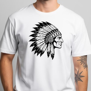 May include: White t-shirt featuring a black and white graphic of a Native American chief in profile, wearing a feathered headdress. The design is a detailed illustration, showcasing the profile of a person with a traditional headdress.