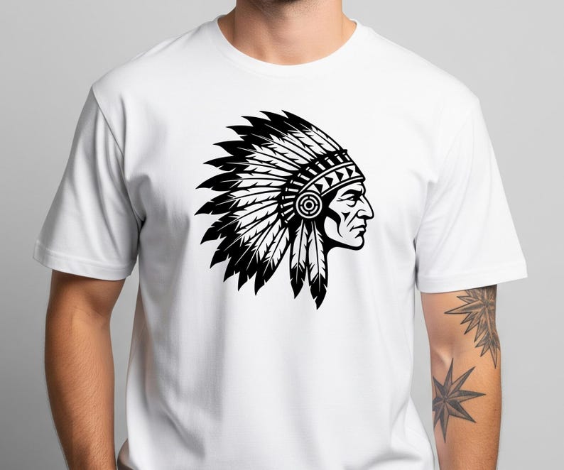 May include: White t-shirt featuring a black and white graphic of a Native American chief in profile, wearing a feathered headdress. The design is a detailed illustration, showcasing the profile of a person with a traditional headdress.
