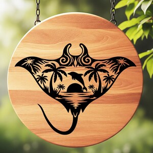 May include: A round wooden sign with a black manta ray design. The design features a dolphin leaping over the sun, palm trees, and ocean waves. The sign is hanging from two chains.
