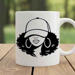 May include: White ceramic mug featuring a black and white graphic of a woman wearing a baseball cap and hoop earrings. The design includes a detailed outline of the woman's face and curly hair. The mug has a curved handle.
