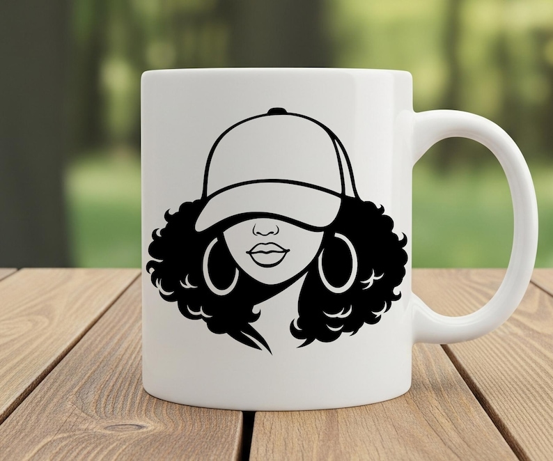 May include: White ceramic mug featuring a black and white graphic of a woman wearing a baseball cap and hoop earrings. The design includes a detailed outline of the woman's face and curly hair. The mug has a curved handle.