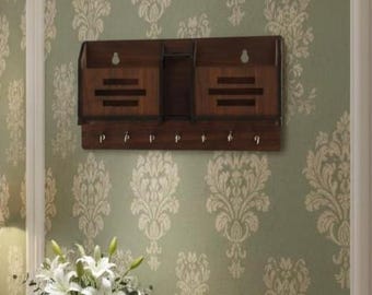 May include: A dark brown wooden wall-mounted organizer with two compartments and six hooks. The organizer has a rectangular shape with horizontal slats on the front of the compartments. It is mounted on a green wallpapered wall.