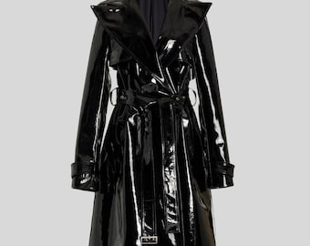 May include: A glossy black trench coat with a wide lapel collar, belted waist, and long sleeves. The coat features a double-breasted design with a buckle closure and a knee-length hemline. The material has a shiny, patent leather appearance.