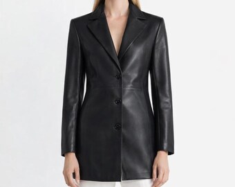 May include: A black leather blazer with a notched collar and three-button closure. The long-sleeved jacket is worn with white pants and black sunglasses. The blazer is a classic, tailored style.