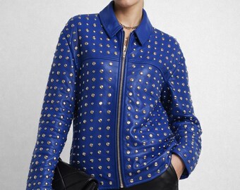 May include: A bright blue jacket featuring a classic collar, a full-length front zipper, and long sleeves. The entire exterior surface of the jacket is densely decorated with numerous small, round, metallic silver studs.