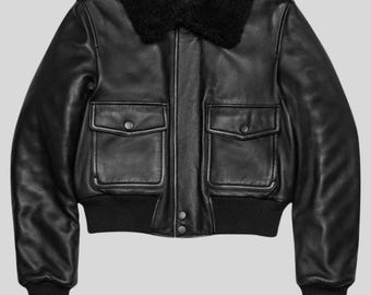 May include: Black leather bomber jacket with a black shearling collar. The jacket features two front pockets with button closures, a ribbed hem, and cuffs. A classic outerwear piece.