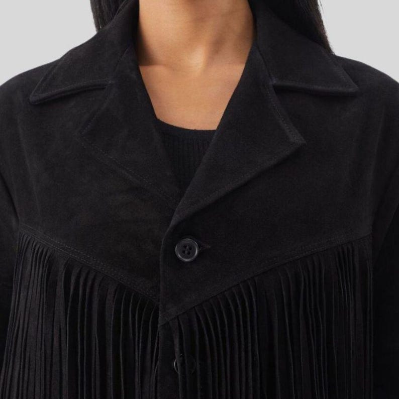 Puede incluir: Chaqueta negra de ante con detalles de flecos. La chaqueta presenta un cuello cl&aacute;sico, un cierre de un solo bot&oacute;n y un ribete de flecos en la parte delantera. La chaqueta es de color negro liso y parece estar hecha de un material suave similar al ante.