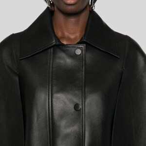 Puede incluir: Chaqueta de cuero negro con cuello ancho y dos botones visibles. La chaqueta tiene un corte entallado y un dise&ntilde;o elegante y minimalista, adecuado para diversas ocasiones.