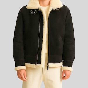 Può includere: Giacca in montone nera con colletto e fodera in montone color crema. La giacca presenta una chiusura con zip frontale, un cinturino con fibbia sul colletto e finiture color crema sui polsini e sull'orlo. Un classico cappotto invernale.