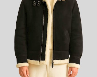 May include: Black shearling jacket with a cream-colored shearling collar and lining. The jacket features a zip-up front, a buckled collar strap, and cream-colored trim on the cuffs and hem. A classic winter coat.