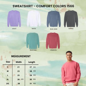 May include: A display of Comfort Colors 1566 sweatshirts in various colors: violet, white, blue jean, pepper, seafoam, and crimson. A measurement chart shows sizes S to 2XL with width and length in inches. A person models a crimson sweatshirt.