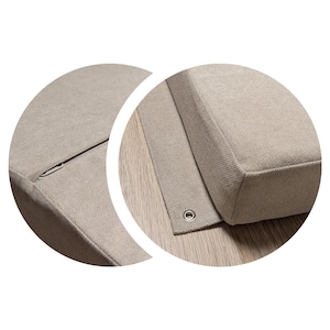 May include: Close-up of a section of a beige upholstered cushion. The fabric has a textured appearance. A metal grommet is visible on the edge of the fabric. The cushion appears to be part of a larger piece of furniture.