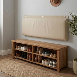 Upholstered wall-mounted backrest in a neutral beige fabric, featuring distinct silver mounting hardware, positioned in an entryway to provide comfortable back support while putting on shoes.