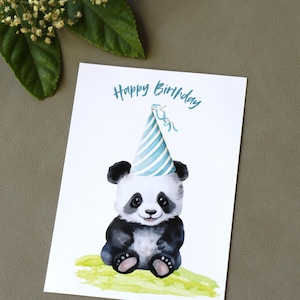 Puede incluir: Tarjeta de cumpleaños con una ilustración en acuarela de un panda con un gorro de fiesta a rayas azules y blancas. Las palabras "Happy Birthday" están escritas en guión turquesa sobre el panda. El panda está sentado sobre un parche verde.