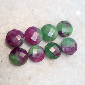 Peut inclure: Huit perles de pierres précieuses facettées. Les perles sont rondes avec un dessus et un dessous plats. Les pierres précieuses sont un mélange de couleurs vertes et magenta. Les facettes créent un effet scintillant. Idéal pour la création de bijoux.