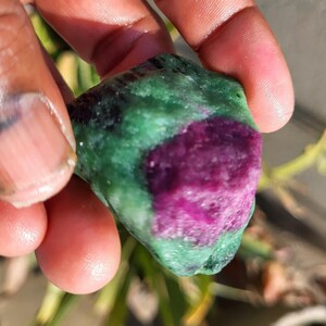 以下が含まれることがあります： 鮮やかな色の組み合わせが特徴の原石。深いマゼンタ色の中心部が、豊かな緑色のマトリックスに囲まれています。自然な質感と色の変化は、未研磨の原石の状態を示唆しています。