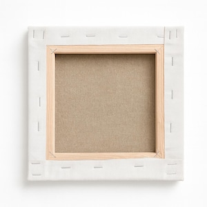 Op de afbeelding: Vierkant canvas gespannen over een houten frame, van achteren bekeken. Het canvas is lichtbeige van kleur, vastgeniet op een houten frame. Het frame is gemaakt van lichtgekleurd hout. Het canvas is omgeven door een witte stof.