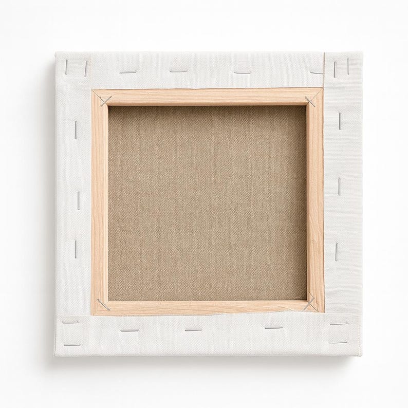 Op de afbeelding: Vierkant canvas gespannen over een houten frame, van achteren bekeken. Het canvas is lichtbeige van kleur, vastgeniet op een houten frame. Het frame is gemaakt van lichtgekleurd hout. Het canvas is omgeven door een witte stof.