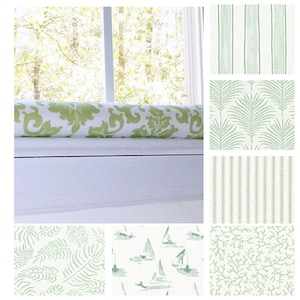 May include: A window seat cushion with a green and white floral pattern is displayed, along with several fabric swatches. The swatches feature various green and white patterns, including stripes, palm leaves, sailboats, and coral.