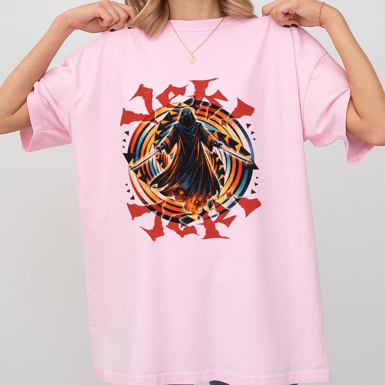 Puede incluir: Camiseta rosa claro con un gr&aacute;fico de una figura encapuchada sosteniendo dos espadas, sobre un dise&ntilde;o circular colorido. El dise&ntilde;o incluye elementos rojos, naranjas, amarillos, azules y negros. La camiseta es de estilo casual y oversize.