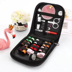 Peut inclure: Trousse de couture noire zipp&eacute;e, ouverte pour r&eacute;v&eacute;ler diverses fournitures de couture. Comprend des bobines de fil de diff&eacute;rentes couleurs, des aiguilles, des ciseaux, un m&egrave;tre ruban et d'autres outils. Un kit compact et organis&eacute;.