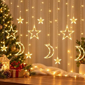 May include: A string of warm white LED curtain lights featuring hanging star and crescent moon shapes. The lights are arranged in vertical strands, creating a glowing display of celestial silhouettes against a soft, illuminated background.