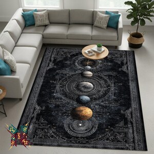 May include: A large, rectangular black area rug with a celestial design featuring planets and astronomical elements. The rug has a detailed, intricate pattern in shades of gray and white, with a border design. The rug is placed in a living room setting.