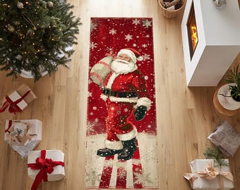 Op de afbeelding: Een rechthoekig kersttapijt met de kerstman in een rood pak met een zak cadeaus over zijn schouder. Het tapijt heeft een rode achtergrond met witte sneeuwvlokken en een gestreept ontwerp aan de onderkant.