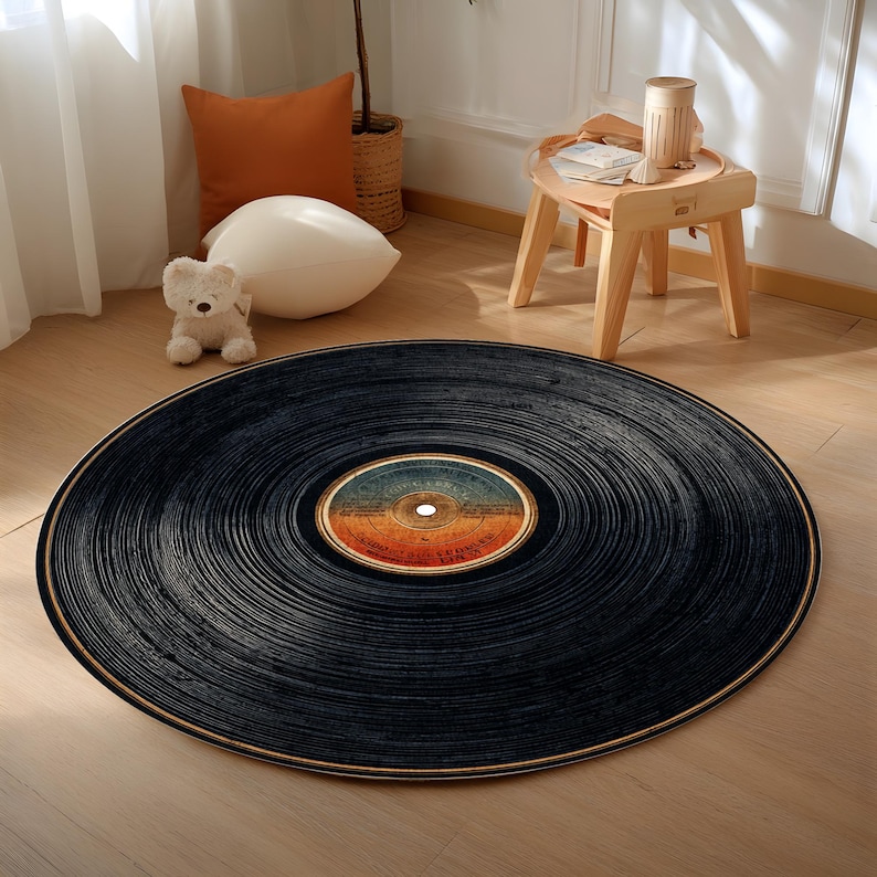 May include: A round black rug designed to resemble a vinyl record. The rug features concentric grooves and a colorful label in the center. The rug is placed on a wooden floor, adding a retro touch to the room.
