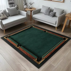 May include: A rectangular area rug designed to resemble a pool table. The rug features a green playing surface, brown and gold trim, and black corner pockets. The rug is placed on a light-colored wooden floor.