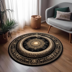 May include: A circular rug with a black background and a gold ouroboros design. The rug features a central medallion with a light-coloured centre and detailed patterns. The snake encircles the medallion, with detailed scales and a serpent head.