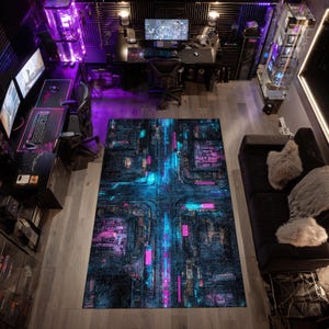 Può includere: Vista aerea di una sala giochi con più configurazioni di computer. Un grande tappeto rettangolare con un design a circuito stampato blu neon e rosa domina il centro. La stanza presenta scrivanie, sedie e torri di computer neri, illuminati da luci viola e blu.