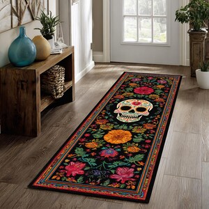May include: A long, rectangular black rug with a Day of the Dead theme. The rug features a colorful skull surrounded by flowers in shades of red, orange, and green. The border has a repeating pattern of colors.