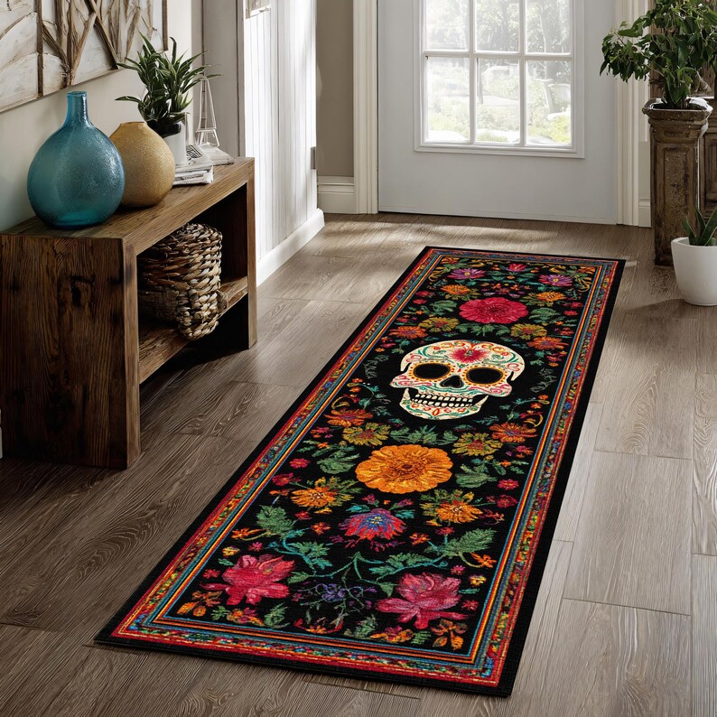 May include: A long, rectangular black rug with a Day of the Dead theme. The rug features a colorful skull surrounded by flowers in shades of red, orange, and green. The border has a repeating pattern of colors.