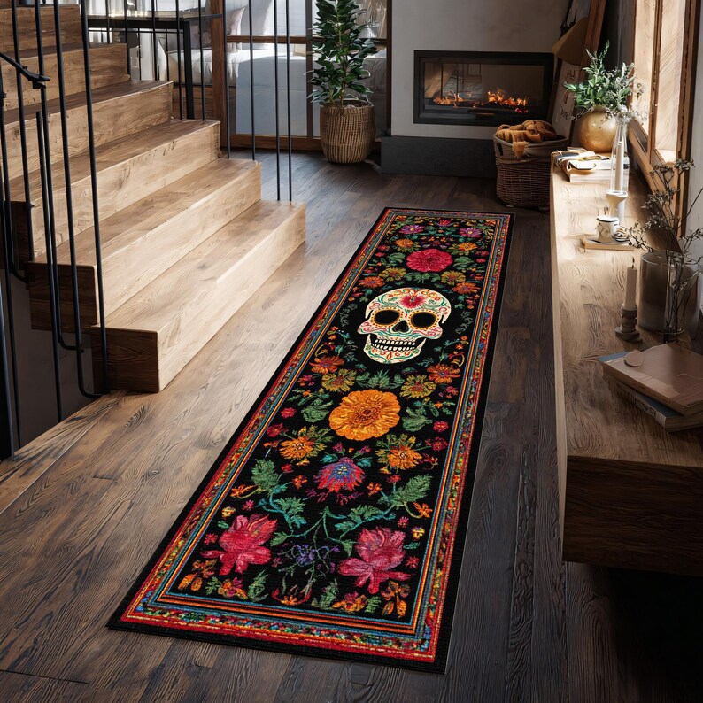 May include: A long, rectangular black rug with a Day of the Dead skull design. The rug is adorned with colorful floral patterns in shades of red, orange, yellow, and green. The rug is placed on a wooden floor.