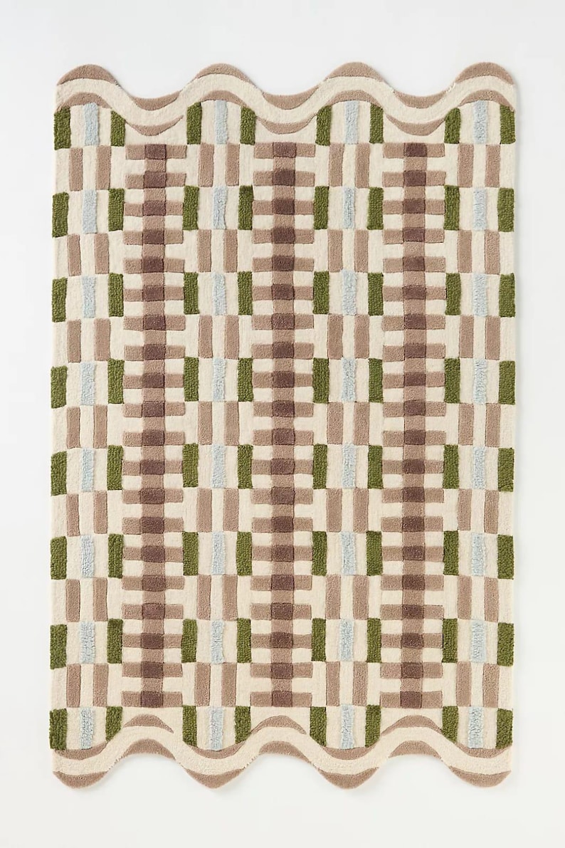 Peut inclure: Un tapis rectangulaire avec une bordure ondul&eacute;e et un motif g&eacute;om&eacute;trique. Le tapis pr&eacute;sente un motif r&eacute;p&eacute;titif de rectangles marron, verts et bleu clair sur un fond cr&egrave;me. Les dimensions du tapis ne sont pas visibles.