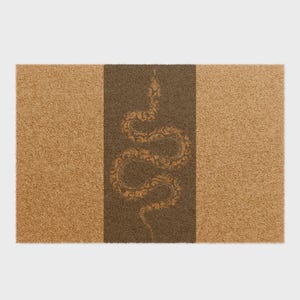 Puede incluir: Una alfombra rectangular con fondo marrón y una franja vertical marrón oscuro. Un diseño detallado de serpiente dorada está centrado en la franja marrón oscuro. La alfombra tiene una superficie texturizada.