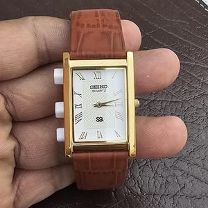 Relógio Seiko Quartz Slim Vintage – Mostrador Clássico com Números Romanos – Caixa Dourada – Pulseira de Couro Não Original (Recondicionado)
