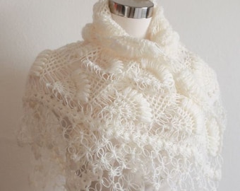 May include: A white crocheted shawl with a delicate floral pattern. The shawl is draped over a white mannequin.